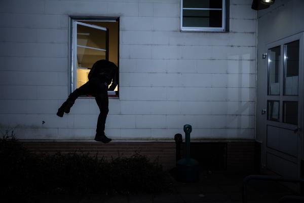 photo d'un cambrioleur sortant d'une fenêtre de maison la nuit