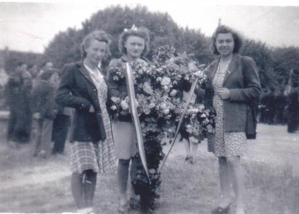 Photo de femmes à la libération portant une croix de lorraine réalisée en fleurs